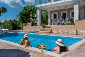 two girls sitting in a swimming pool at Villa Antonio in Romírion +13 photos
