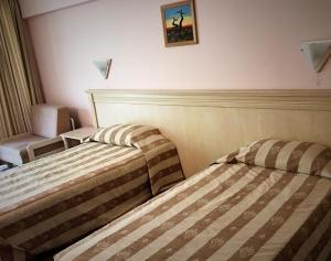 a hotel room with two beds and a chair at Hotel OTDIH in Kavarna