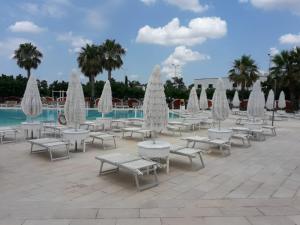 a group of tables and chairs with umbrellas at Villetta Residence Chiusurelle in Porto Cesareo