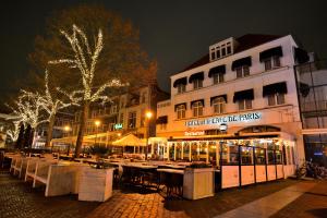 a group of tables in front of a building at night at Hotel et le Cafe de Paris in Apeldoorn