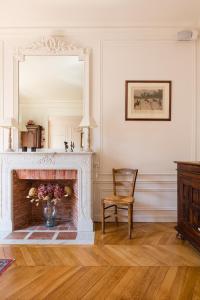 パリにあるVeeve - Avenue to the Eiffel Towerの鏡と椅子付きの暖炉のある部屋