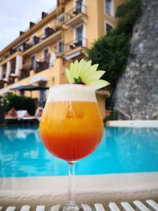 a drink sitting on a table next to a pool at Hôtel La Pérouse Nice Baie des Anges - Recently fully renovated in Nice