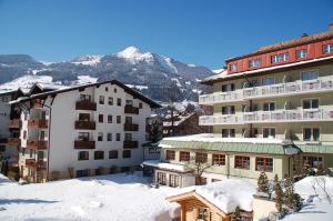 a group of buildings in the snow with a mountain at Hotel Rauscher und Paracelsus in Bad Hofgastein