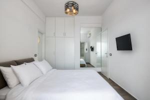 een witte slaapkamer met een groot bed en een televisie bij Theano Cave Suites & Villas in Imerovígli