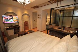 1 dormitorio con 1 cama blanca grande y TV en Praha Boutique Hotel en Changwon