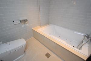 a white bathroom with a tub and a toilet at Praha Boutique Hotel in Changwon