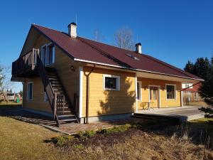 a small yellow house with a porch and a staircase at Soomaa Canoe Trips Centre in Tohera