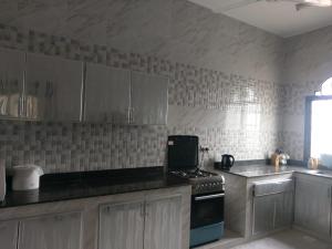 a kitchen with white cabinets and a stove top oven at Alarbee Aljeded in Salalah