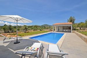 uma piscina com duas cadeiras e um guarda-sol em Villa Ses Veyetes em Artà