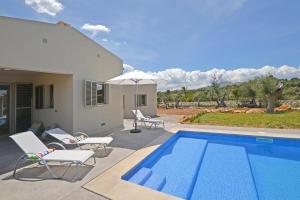 uma piscina com cadeiras e um guarda-sol ao lado de uma casa em Villa Ses Veyetes em Artà