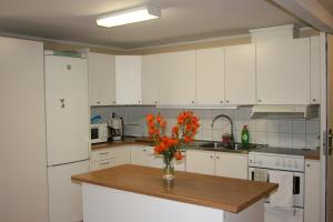 a kitchen with white cabinets and a vase of flowers on a counter at Modal Annex in Hultsfred