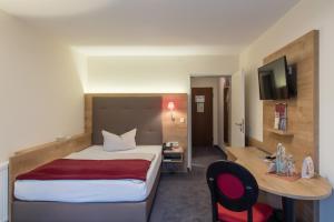 a hotel room with a large bed and a desk at Hotel St. Georg in Bad Aibling