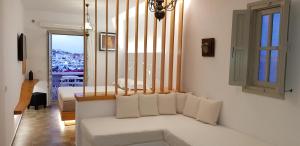 a living room with a white couch and a window at Vrahos Boutique Hotel in Karavostasi
