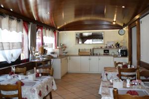 a dining room with two tables and a kitchen at Hotel de la Gare in Monthey