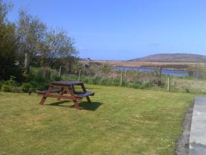 a picnic table sitting in the grass near the water at Riverside Cottage in Lochboisdale