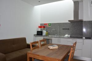 a kitchen with a wooden table and a couch at Just Natur Guesthouse in Castro Laboreiro