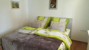 a bed with green and gray sheets and pillows at Ferienwohnung Miezerle in Steißlingen