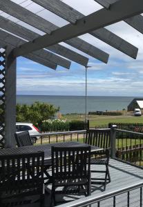 a table and chairs on a deck with a view of the ocean at Craster Crew House in Craster