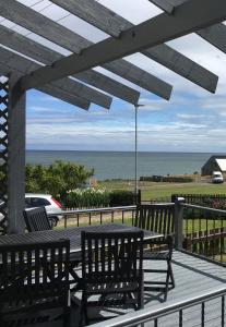 a table and chairs on a deck with a view of the ocean at Craster Crew House in Craster
