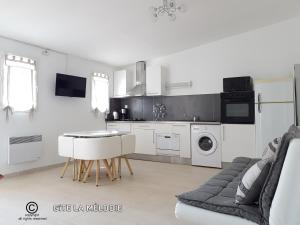 a kitchen with white appliances and a table and chairs at Gîte La mélodie in Longueville
