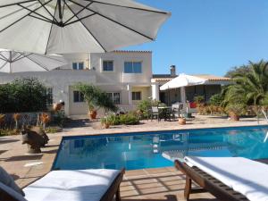 a swimming pool with an umbrella and a house at Apartamentos Casa Romantica in La Savina