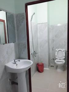 a bathroom with a sink and a shower with a toilet at Khách sạn Ngọc Quỳnh in Lagi