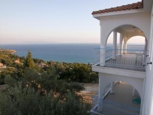 a white house with a balcony overlooking the ocean at Folies in Lourdata