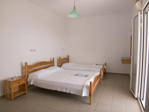 two twin beds in a room with white walls at Folies in Lourdata