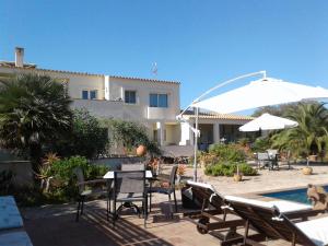 een terras met stoelen, een tafel en een parasol bij Apartamentos Casa Romantica in La Savina