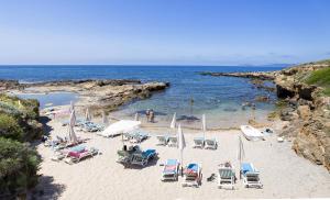 uma praia com cadeiras e pessoas na água em Balaguer House em Alghero