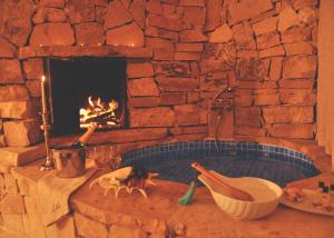 a stone fireplace with a jacuzzi tub in a room with a fireplace at Lethe Exclusive Hotel in Agva