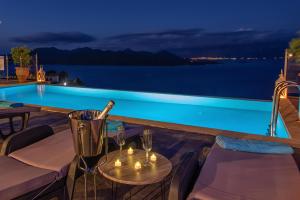 een tafel met kaarsen en wijnglazen op een balkon met een zwembad bij Ionian Heaven Villas in Nikiana