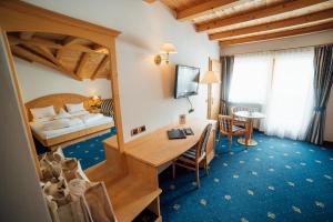 a hotel room with a bedroom and a desk and a bed at Hotel Pra Tlusel in Selva di Val Gardena
