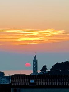 a clock tower with the sunset in the background at Apartments Padovan in Rab