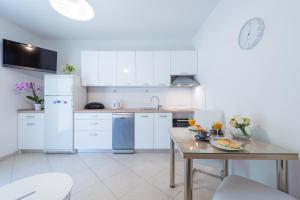 a kitchen with white cabinets and a table with food on it at Apartman Lu in Mokošica