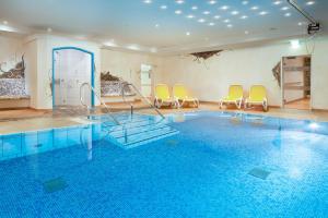 um quarto com uma piscina com cadeiras e uma piscina em "Haus Berktold" - Annehmlichkeiten von 4-Sterne Familien-und Wellnesshotel Viktoria können mitbenutzt werden em Oberstdorf
