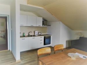 a kitchen with white cabinets and a table and chairs at Pension Apartments Klotznerhof in Schenna +46 photos