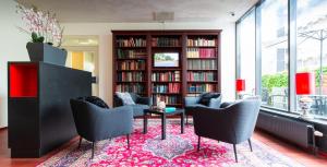 a library with chairs and a table on a rug at Bastion Hotel Leiden Oegstgeest in Oegstgeest