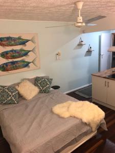 Un dormitorio con una cama con almohadas peludas y una pintura en SEA-esta, en Nelly Bay