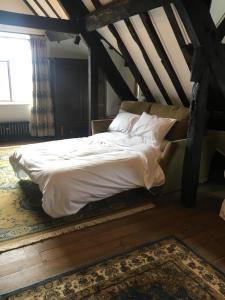 a bedroom with a bed with white sheets and a window at Bishop Percys House in Bridgnorth