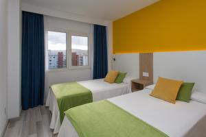 a hotel room with two beds and two windows at Aparthotel Acuasol in Peñíscola