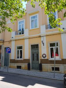 um edifício amarelo com portas e janelas verdes em Guest House do Largo em Faro