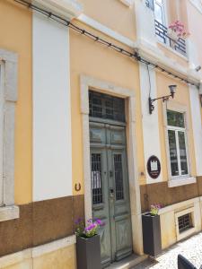 un edificio con una puerta verde y dos ventanas en Guest House do Largo, en Faro