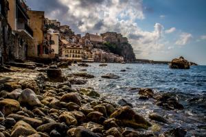a rocky beach with buildings and the ocean at Piana delle Galee in Scilla