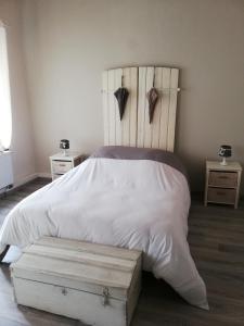 a bedroom with a white bed with a wooden headboard at La petite douane in Massembre