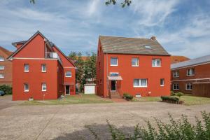 a red house next to two brick buildings at Hotel Atlantis in Norddeich