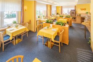 a restaurant with tables and chairs with yellow walls at Hotel Atlantis in Norddeich