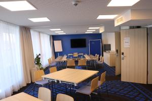 une salle de conférence avec des tables, des chaises et une télévision dans l'établissement IBB Hotel Paderborn, à Paderborn