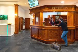 Best Western Ahorn Hotel Oberwiesenthal – Adults Only في كورورت أوبرفايسنتال: رجل يقف عند بار في صالون حلاقة