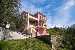 une maison rose avec un balcon latéral dans l'établissement Ionian Mare, à Lakíthra